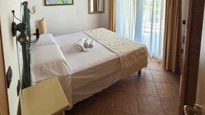 Un dormitorio con techo de madera, una cama con cubrecama blanco, un cuadro en la pared y una ventana con cortinas.