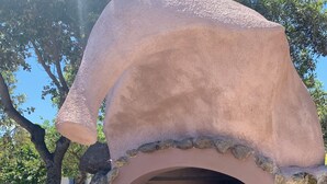 Horno de piedra al aire libre con base de ladrillo y techo de piedra.