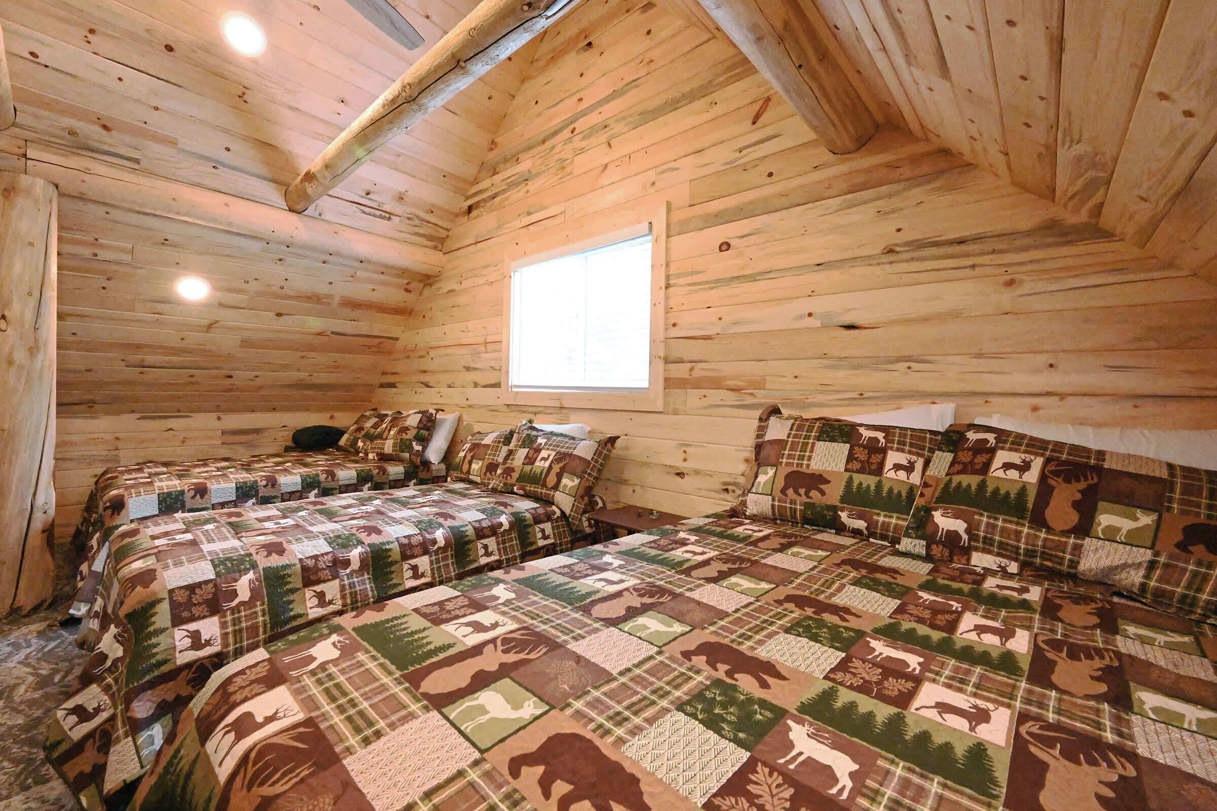 Une cabine  équipée de deux lits, chacun recouvert d’une couverture matelassée ornée de motifs animaliers.