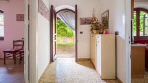 Un pasillo con una puerta que da a un espacio exterior, un armario de madera y una silla.