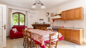 Una cocina acogedora con armarios de madera, una mesa de comedor con sillas, un sofá rojo y una ventana con cortinas.