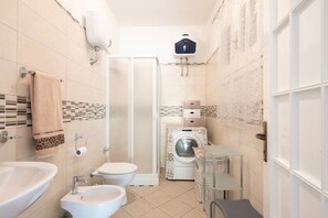 Baño pequeño con lavabo, inodoro y lavadora.