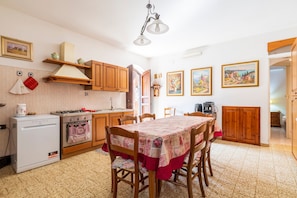 A kitchen with wooden cabinets, a dining table with a tablecloth, and a stove.