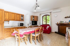 A kitchen with wooden cabinets, a dining table with chairs, a red sofa, and a window with curtains.
