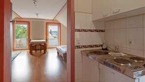 A kitchen with a sink, stove, and cabinets, a dining area with a table and chairs, and a view through a glass door. - Apartment 'Apfelbaum' with Balcony and Wi-Fi (Obersulm)