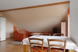 Ein Zimmer mit Hochbett, einer Couch, einem Esstisch und Stühlen.