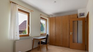 Een kamer met een bed, een bureau, een stoel, een kledingkast en een raam.