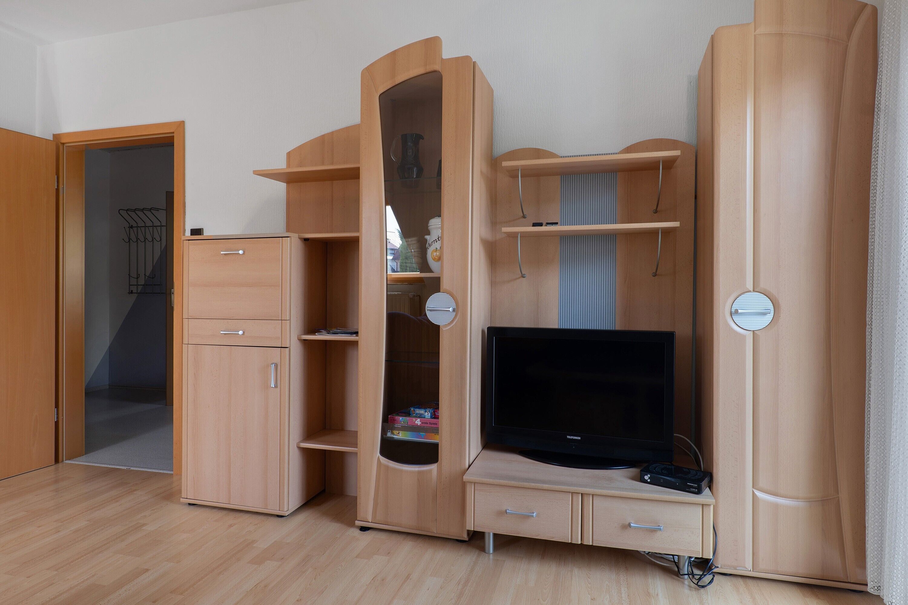 Una stanza con un armadio in legno, un televisore e una porta che dà su un'altra stanza.