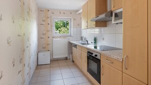 Eine Küche mit Holzausstattung, einer Mikrowelle, einem Fenster und einem Kühlschrank.