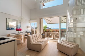Ein modernes Interieur mit einer Couch, einem Essbereich und Meerblick.
