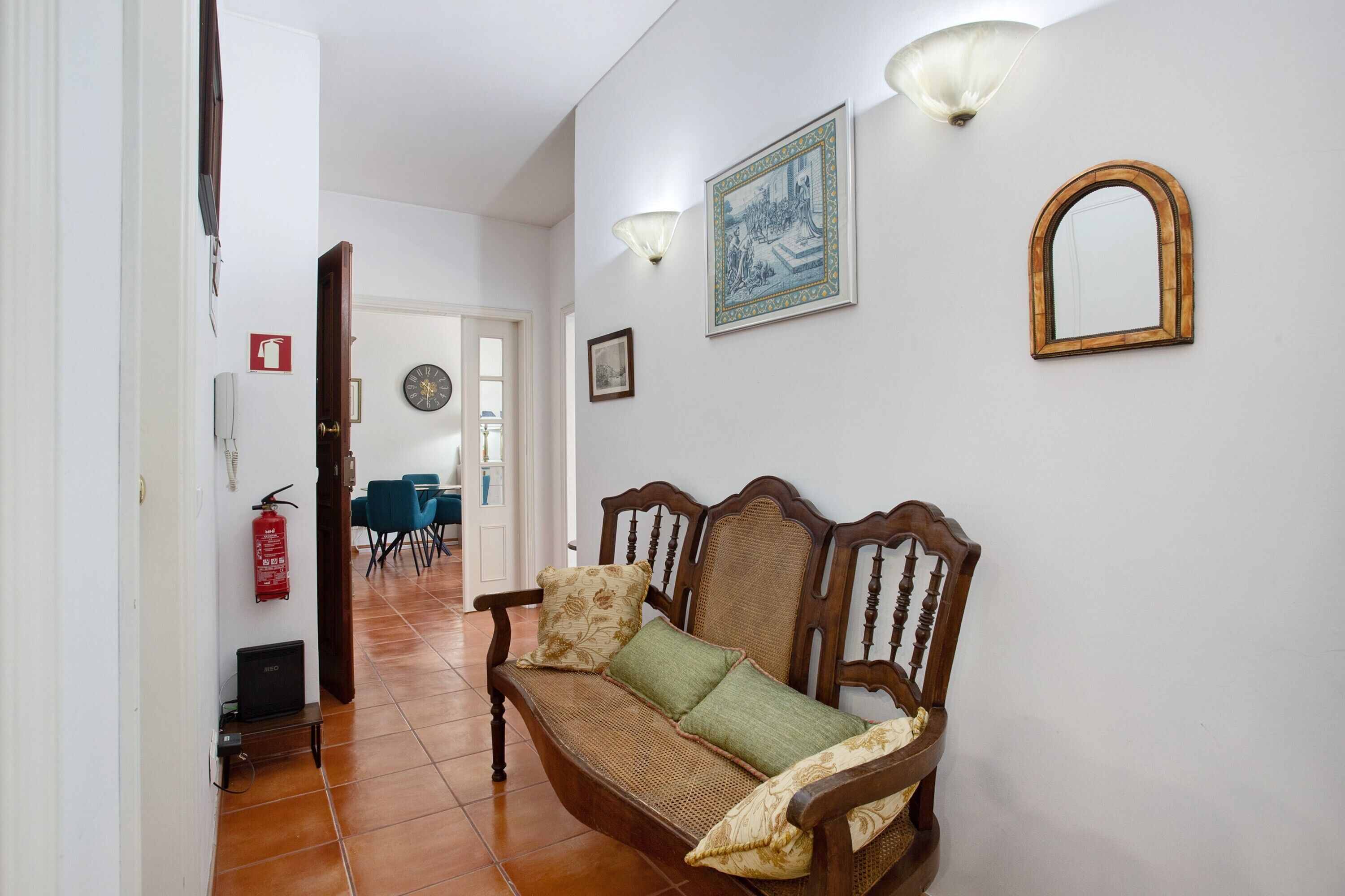 A hallway with a wooden bench, a wall-mounted mirror, and a framed picture.