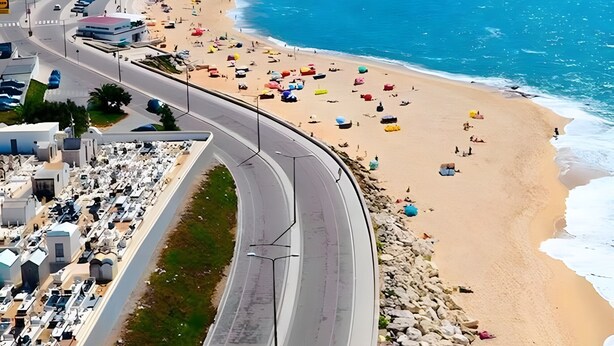 Une route côtière, avec une plage d’un côté et des bâtiments de l’autre.