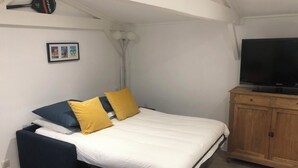 A bedroom with a bed, a TV, a wooden cabinet, and a framed picture on the wall.