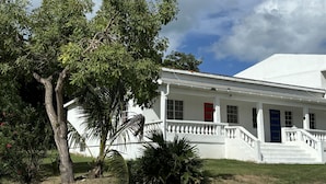 A white building with a red door, white columns, and a white staircase leading to the entrance.
