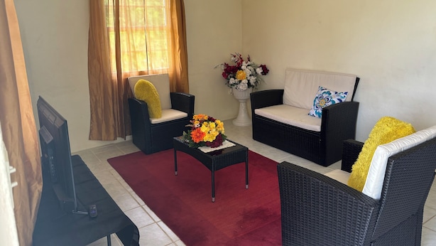 A living room with two black wicker sofas, a small coffee table, and a TV stand.