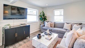 A modern living room with a grey sectional sofa, a white coffee table, and a black cabinet.