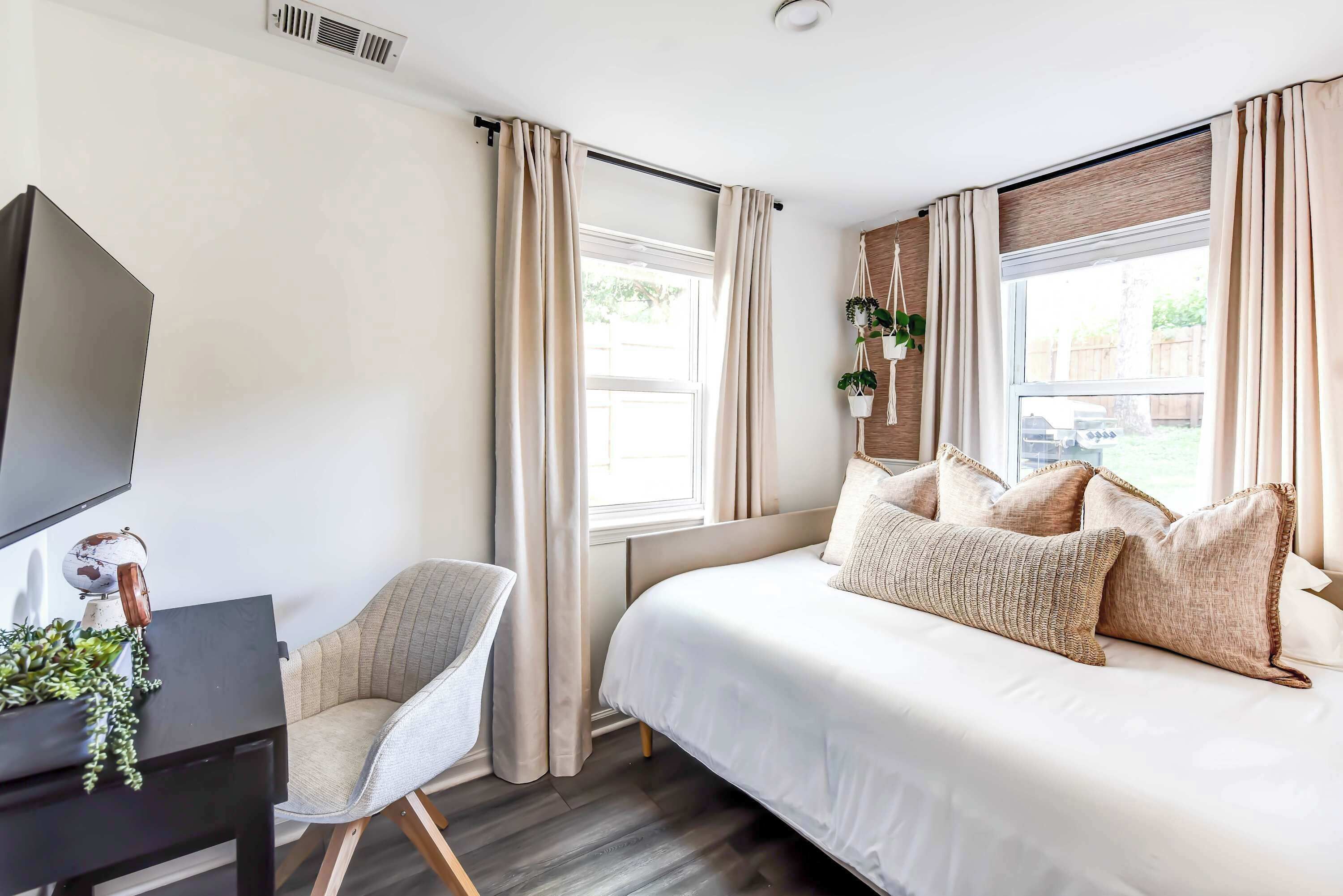 A bedroom with a bed, a desk, a chair, and a TV.