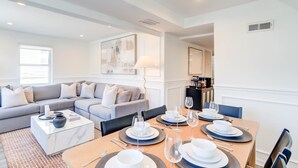 A modern living room with a sofa, coffee table, and dining area set up for a meal.