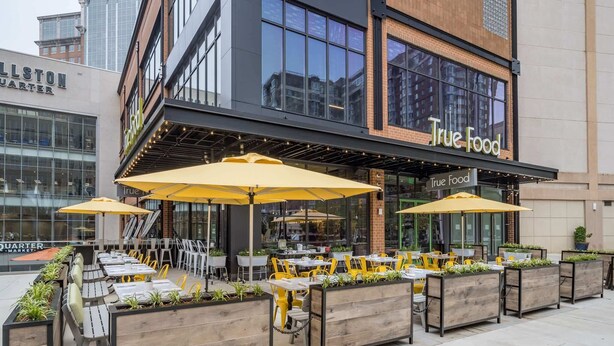 An outdoor dining area with yellow umbrellas and wooden planters.