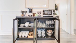 A modern kitchen with a built-in coffee station, including a coffee machine and a microwave.