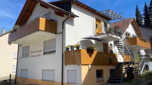 A two-story building with a balcony, a staircase, and a sign indicating it is a guesthouse. - Apartment 'Erdgeschoss' with Mountain View, Shared Terrace and Wi-Fi (Metzingen)