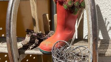 Una jardinera en forma de bota roja con suculentas, una jaula de pájaros metálica y un banco de madera.