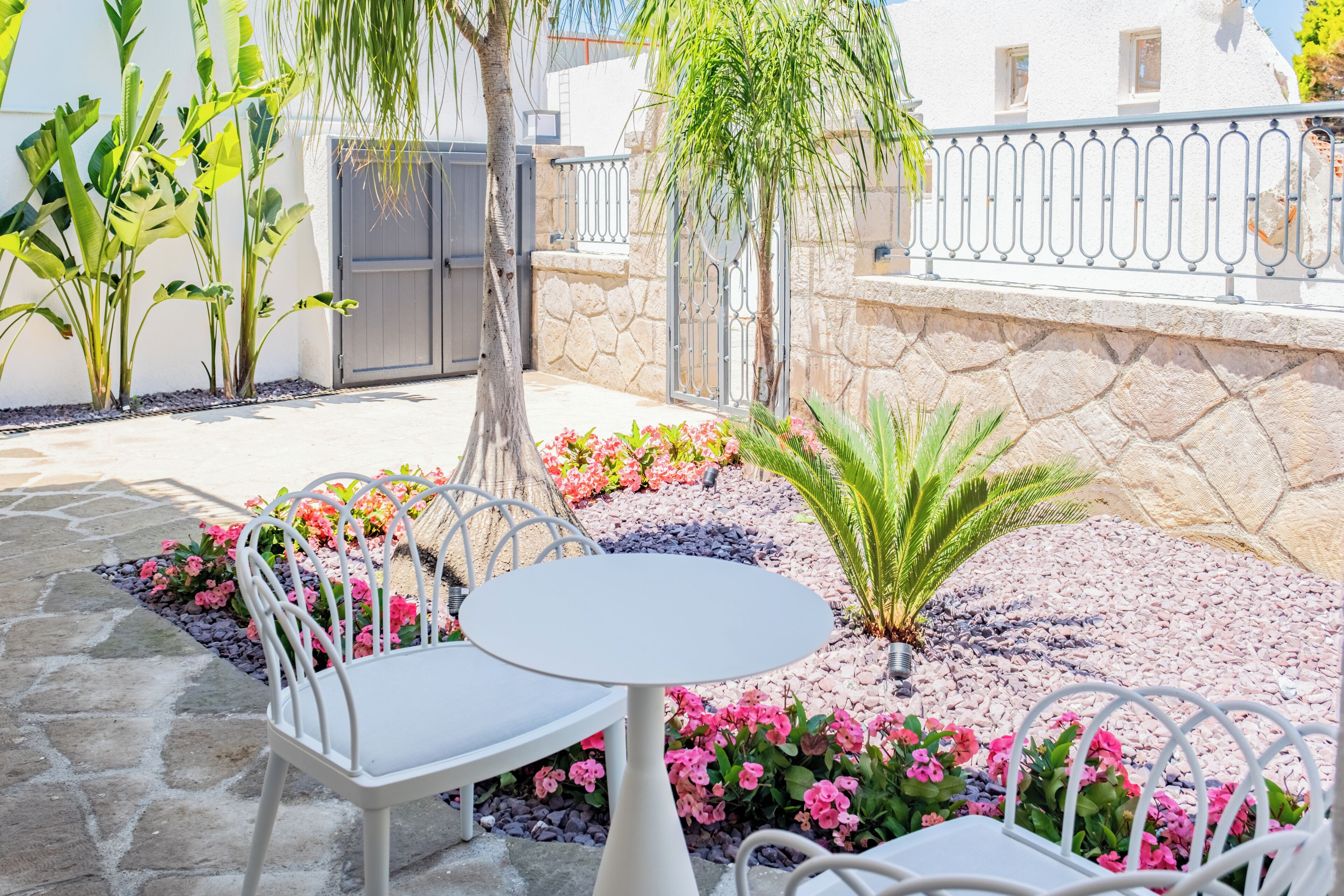 Un patio con mesa y sillas, rodeado de plantas y flores.