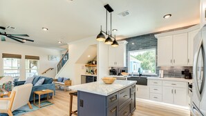 A modern kitchen with a central island, built-in cabinets, and a large window.