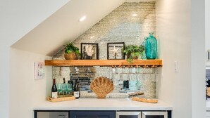 A kitchen with a brick backsplash, wooden shelves, and a built-in refrigerator.