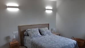 A bedroom with a bed, two bedside tables, a lamp, a basket, and a wall-mounted light fixture. - T2 house with small adjoining plot, very nice. (Sète)