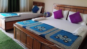 A hotel room with a large bed, two smaller beds, and a wooden headboard. - Hotel Vijay Residency Barkot (Rajgarhi)