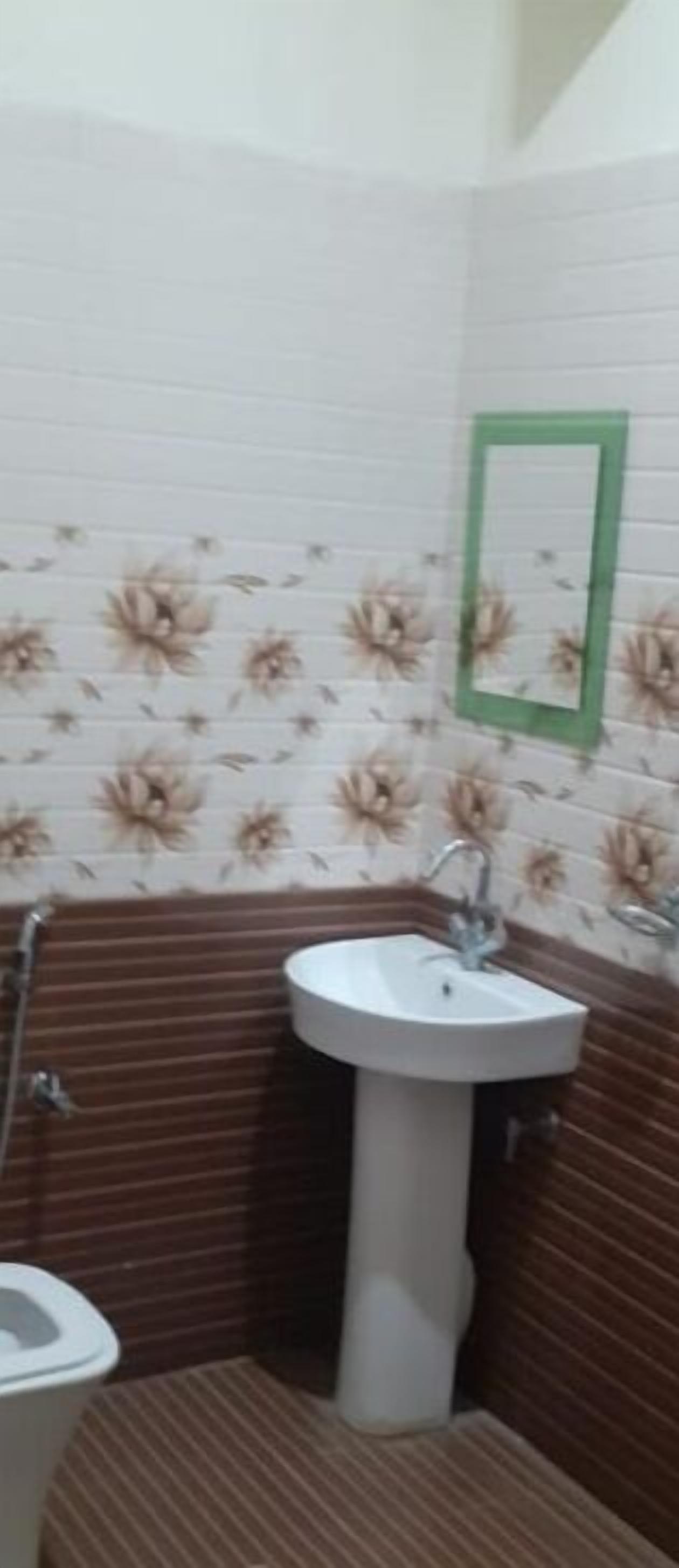Une salle de bain avec un lavabo blanc, un miroir et des carreaux muraux à motifs floraux.