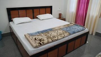 Una cama con cabecera de madera, una manta estampada y almohadas blancas.