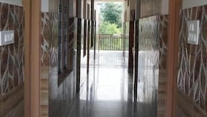 A corridor with patterned walls and a tiled floor, leading to a balcony with a view of greenery. - Hotel Vijay Residency Barkot (Rajgarhi)