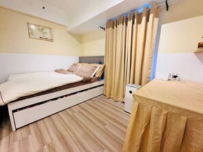 A bedroom with a bed, a small table, a heater, and a curtain. - Cozy Vibes Retreat in Makati (Makati)