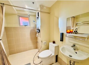A bathroom with a shower, toilet, sink, and a window with a view. - Cozy Vibes Retreat in Makati (Makati)