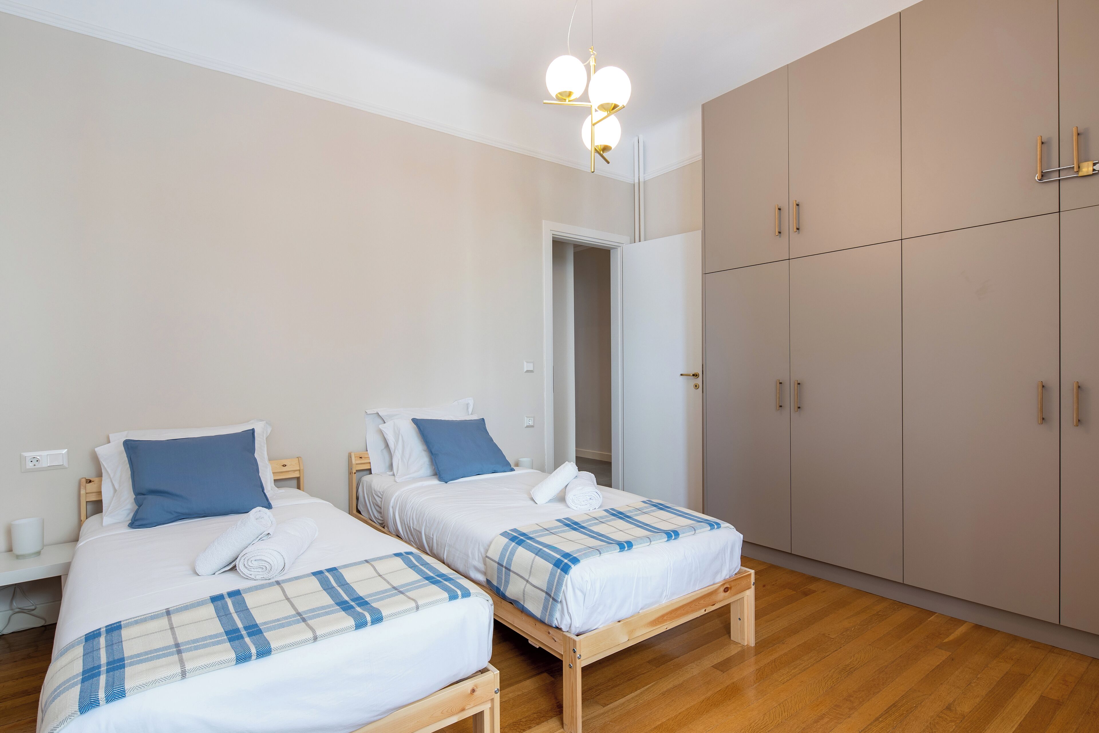 Een slaapkamer met twee bedden, een kledingkast en een plafondlamp.