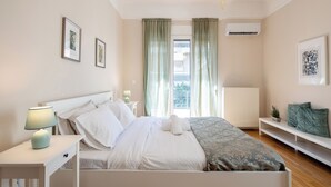 A bedroom with a bed, bedside tables, a nightstand, a lamp, a window with curtains, and wall art. - Spark 2-Bedroom Apartment in Athens (Athens)