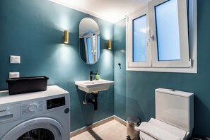 Un bagno moderno con lavatrice, lavandino, water e finestra con vetro smerigliato.