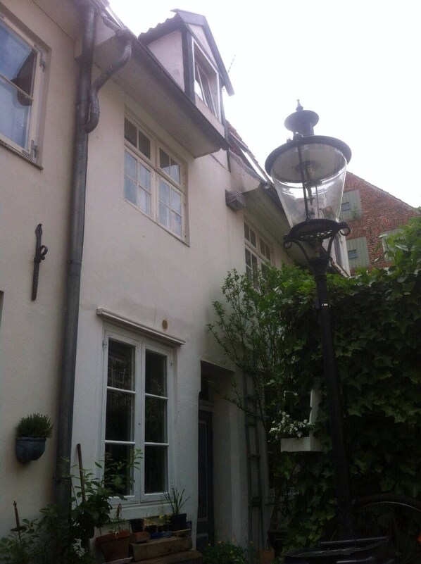 A building with a white facade, multiple windows, and a traditional street lamp. - The Lübeck Ganghausperle 60sqm is a small pearl on the old town island (Lübeck)