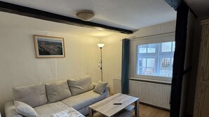 Una sala de estar con un sofá, una mesita de centro, una lámpara de pie y una ventana con vistas al exterior.