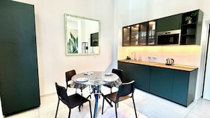 Une cuisine compacte avec un coin repas, comprenant une table ronde avec des chaises, un miroir et des placards intégrés.
