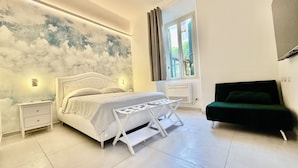 Une chambre à coucher avec un lit, une table de chevet, un bureau, une chaise et une fenêtre avec des rideaux.