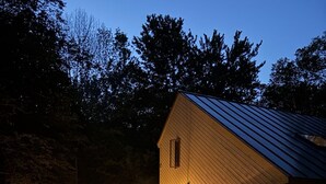 A wooden cabin with a porch, outdoor seating, and string lights. - Cozy 3BR Retreat w/ Resort Perks - Pools, Hot Tub, & Skiing! (Campton)