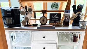 A wooden-framed coffee station with a Keurig coffee maker, mugs, a clock, a welcome sign, and baskets of books and glasses. - Cozy 3BR Retreat w/ Resort Perks - Pools, Hot Tub, & Skiing! (Campton)