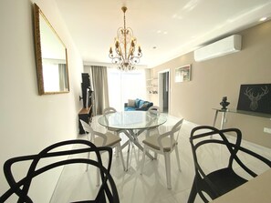 Ein Essbereich mit einem Glastisch und Stühlen, einer Kandelaber und einem modernen Interieur.