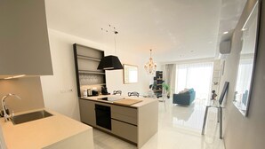 Een moderne keuken met een inbouwvaatwasser, een spoelbak en een eethoek met een glazen tafel en stoelen.