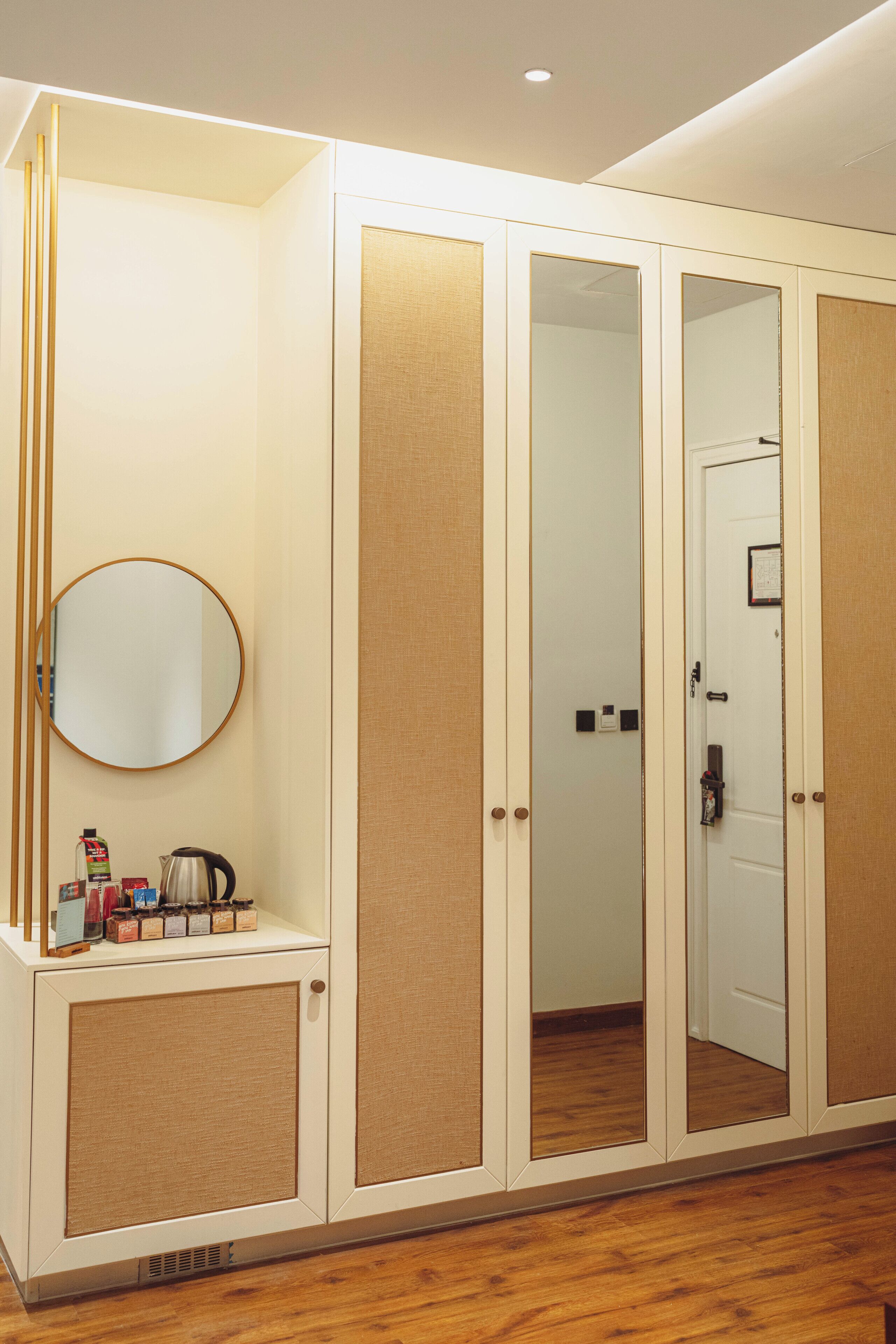 A room with a wardrobe, a mirror, and a small cabinet with items on it.