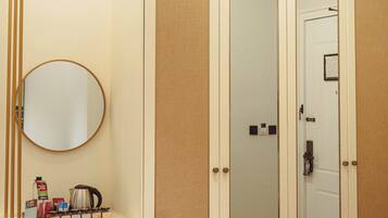 A room with a wardrobe, a mirror, and a small cabinet with items on it.