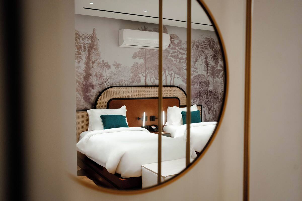 A hotel room with a bed, a nightstand, and a wall-mounted air conditioner.